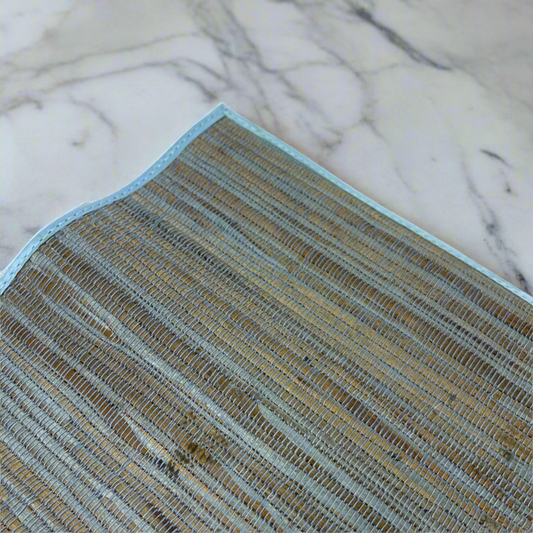 These Handwoven Blue Citra Water Hyacinth Placemat - Set of 4 are sure to elevate any table setting. Crafted from Water Hyacinth with striking blue and natural tones, they can easily fit into many palettes, while providing protection to your tabletops. Corner close up.