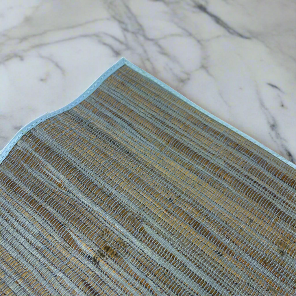 These Handwoven Blue Citra Water Hyacinth Placemat - Set of 4 are sure to elevate any table setting. Crafted from Water Hyacinth with striking blue and natural tones, they can easily fit into many palettes, while providing protection to your tabletops. Corner close up.