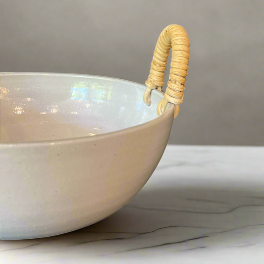 Our Rimbah Ceramic & Rattan Bowl is a beautifully handmade, tactile piece, with qualities that are evident in its organic shape and distinctive glazed finish. The subtle cream stoneware accented by Rattan handles brings a stylish aesthetic to your table.