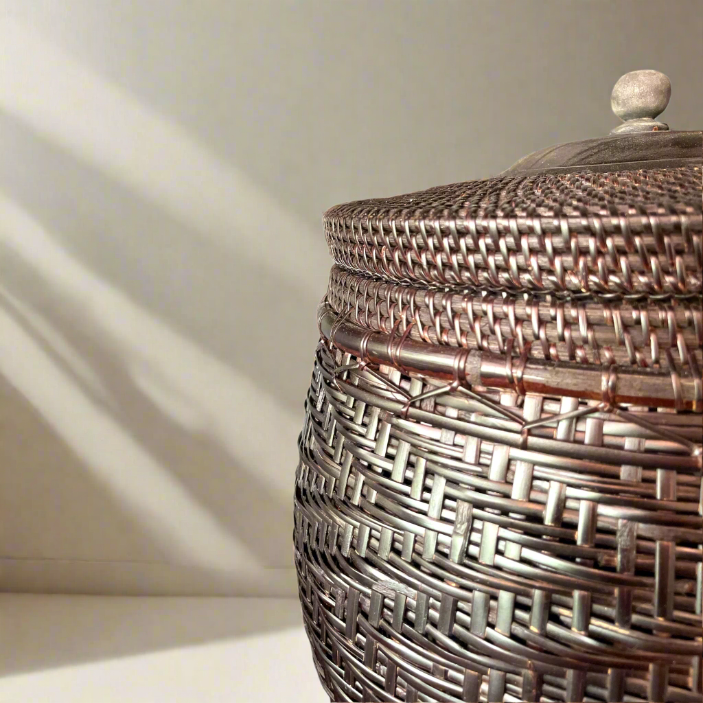 Crafted by skilled artisans from East Indonesian Island Villages using locally-sourced rattan and bamboo, the Cahyono Handmade Rattan & Bamboo Basket is visually stunning and exceptionally functional. Their deep, rich brown and black colour is complemented by a sturdy lid and wooden handle, making them the perfect choice for decorative accents or convenient storage solutions. Close up detail.