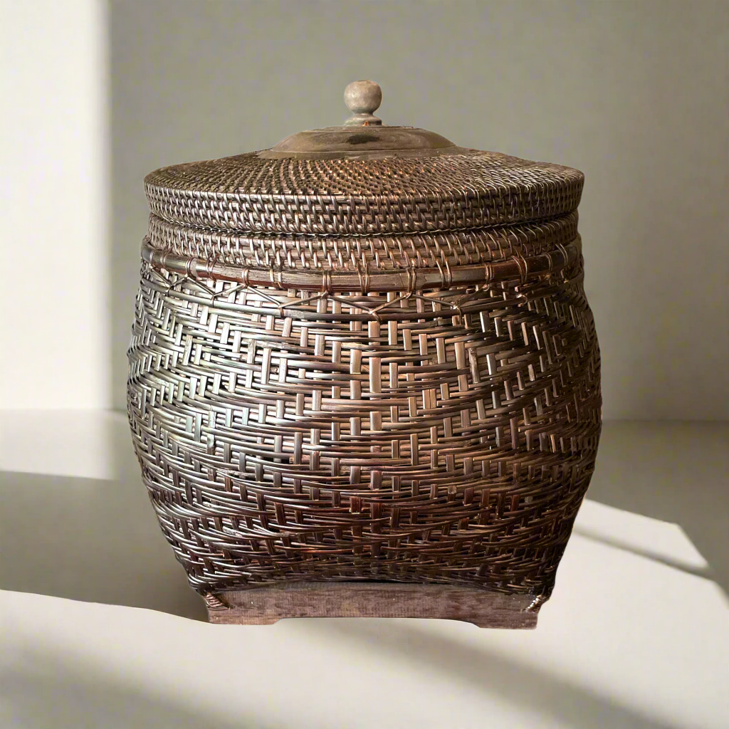 Crafted by skilled artisans from East Indonesian Island Villages using locally-sourced rattan and bamboo, the Cahyono Handmade Rattan & Bamboo Basket is visually stunning and exceptionally functional. Their deep, rich brown and black colour is complemented by a sturdy lid and wooden handle, making them the perfect choice for decorative accents or convenient storage solutions. Front.