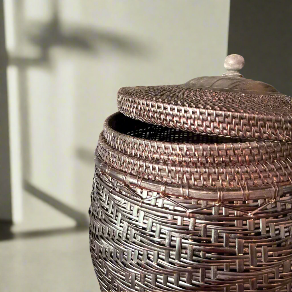 Crafted by skilled artisans from East Indonesian Island Villages using locally-sourced rattan and bamboo, the Cahyono Handmade Rattan & Bamboo Basket is visually stunning and exceptionally functional. Their deep, rich brown and black colour is complemented by a sturdy lid and wooden handle, making them the perfect choice for decorative accents or convenient storage solutions. Close up.
