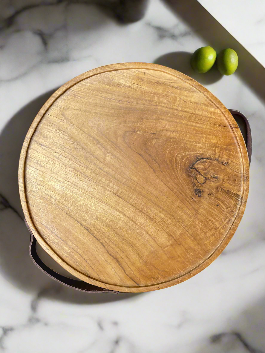 Organic yet sophisticated, this circular tray is crafted from teak wood and leather. Used as a serving tray while entertaining, or as an added layer for styling your coffee table decor, its natural knots and grains paired with the deep tone of leather create a beautiful, refined material mix. Top