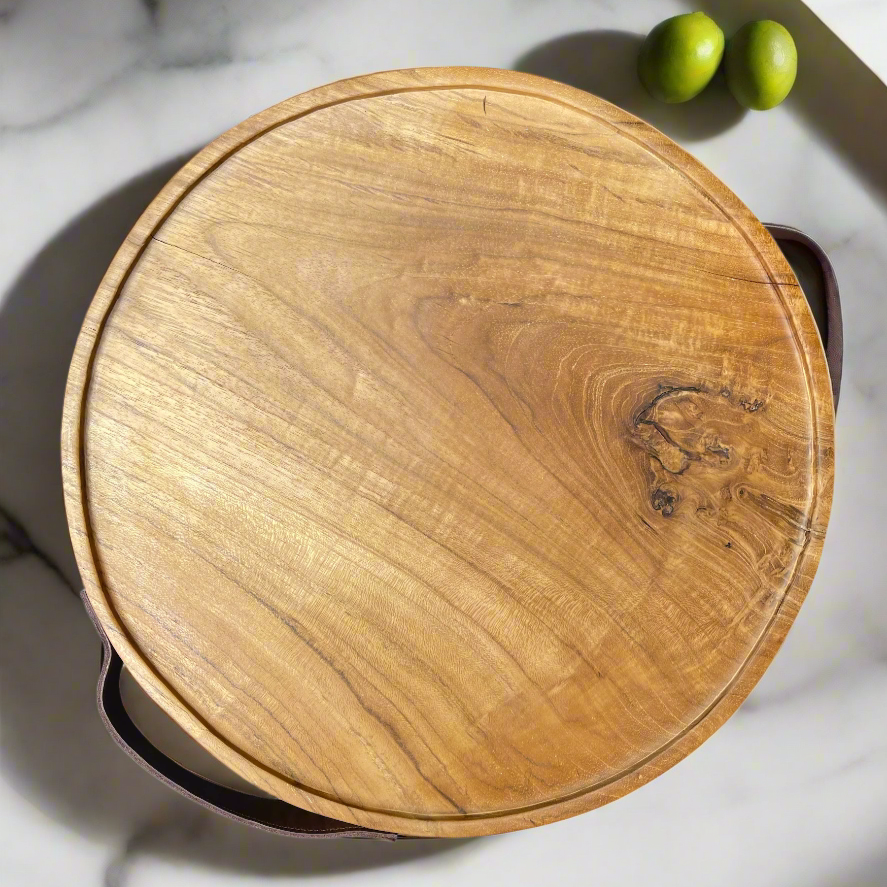 Organic yet sophisticated, this circular tray is crafted from teak wood and leather. Used as a serving tray while entertaining, or as an added layer for styling your coffee table decor, its natural knots and grains paired with the deep tone of leather create a beautiful, refined material mix. Top