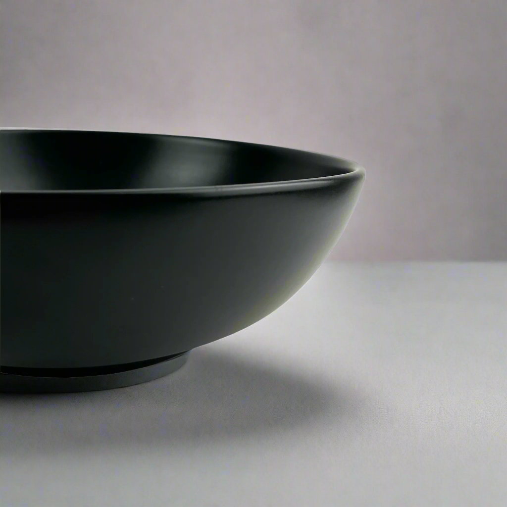 Experience the simplistic elegance of our Handcrafted Black Jenis Bowl, designed with a smooth and gentle edge for a touch of refinement. Detail.