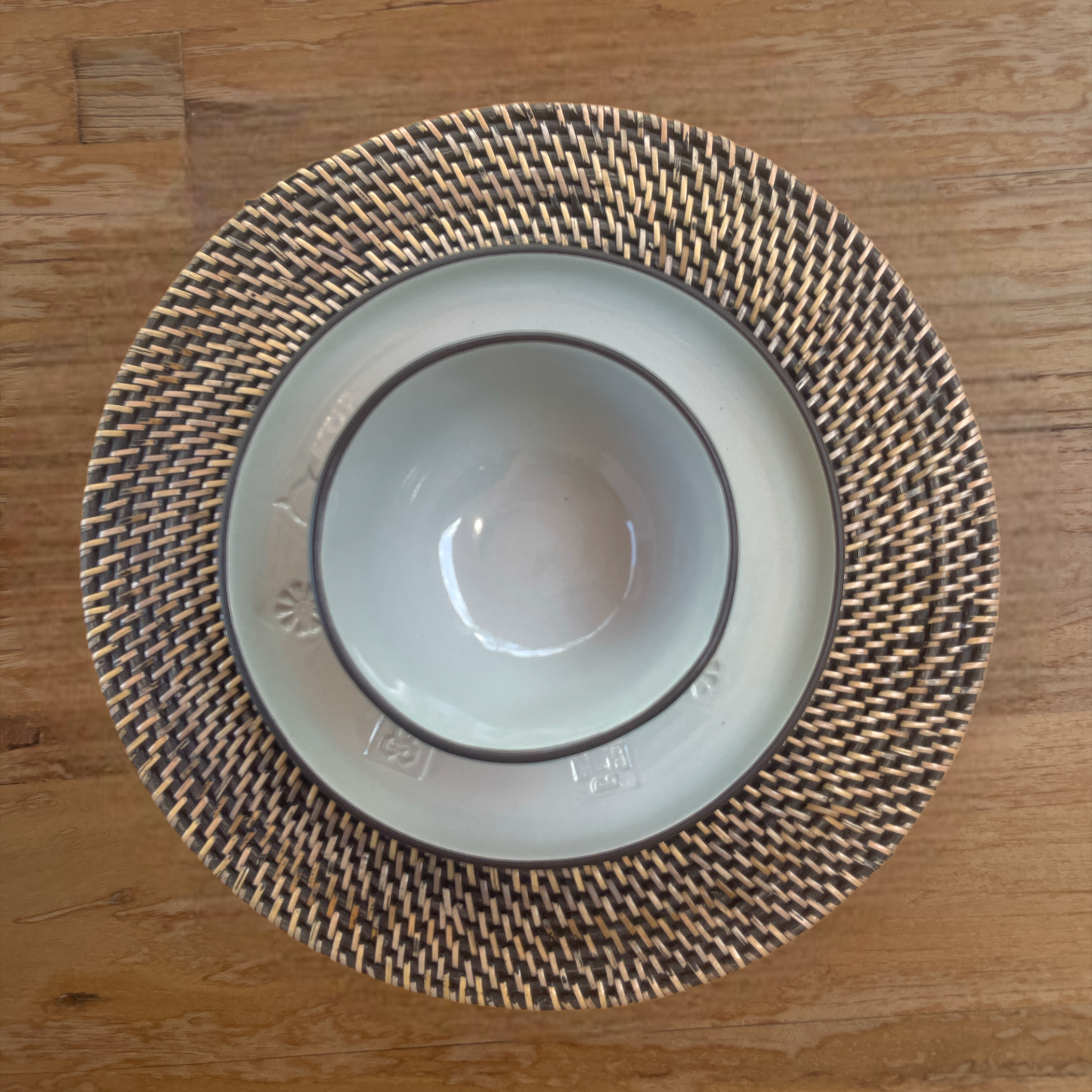 Transform your table into a work of art with our exquisite Handwoven Putih Rattan Black and Natural Round Placemat. Styled top angle.