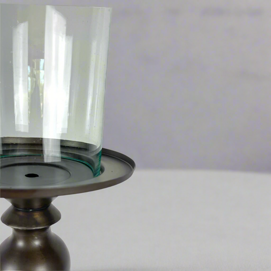 Crafted from bronzed copper, the elegant contours of our Tembaga Copper Candle Holder has a refined elegant feel. The classic design displays a church pillar candle perfectly, creating a soft ambient aesthetic. Close up.