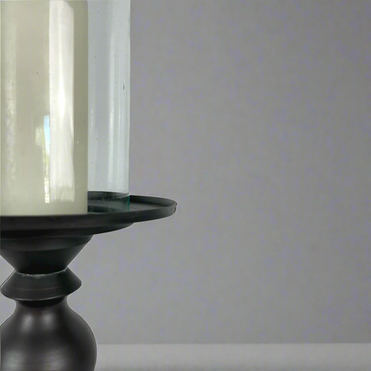 Crafted from bronzed copper, the elegant contours of our Rocca Copper Candle Holder has a refined elegant feel. The classic design displays a church pillar candle perfectly, creating a soft ambient aesthetic. Close up.