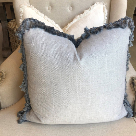 Indulge in the superior comfort of Warwick Fabrics heavyweight textile, found in this luxurious Husk Ice Blue Grey Tassel Fringe Cushion. Its sumptuous pale hue is enhanced with a tassel fringe, adding exquisite texture and flair. Enjoy the snuggly embrace of its luxurious feather insert.