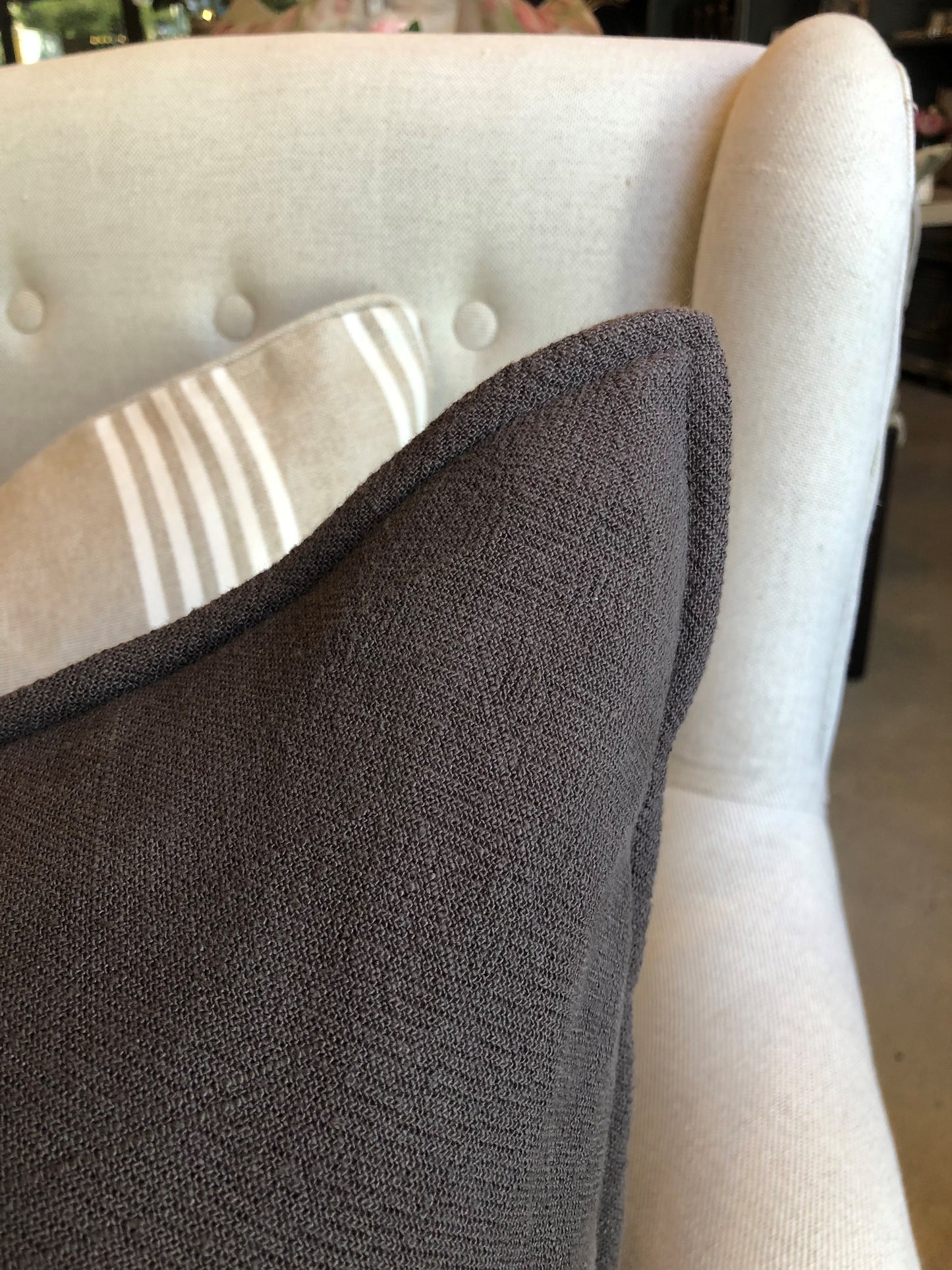 The plush feather-filled Oban Herringbone Woven Stonewashed French Linen Cushion showcases a classic charcoal coloured pattern woven from French Linen which has been stonewashed to achieve a soft luxurious feel. Corner close up.