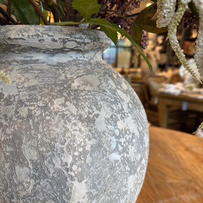 Close-up of a textured stone sphere with plants in the background