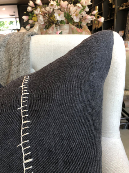 Our Amber Linen Hand-Embroidered Charcoal Cushion has been specifically crafted with meticulous detail and casual living in mind. This muted black cushion with its contrast handcrafted blanket stitch adds a stylish touch to any high-traffic area, providing both durability and comfort. Its exclusive plump feather insert guarantees the most comfortable seating experience, while its 100% linen composition ensure quality. OEKO-TEX® and GOTS certified, this cushion is a smart addition to any space. Close up.