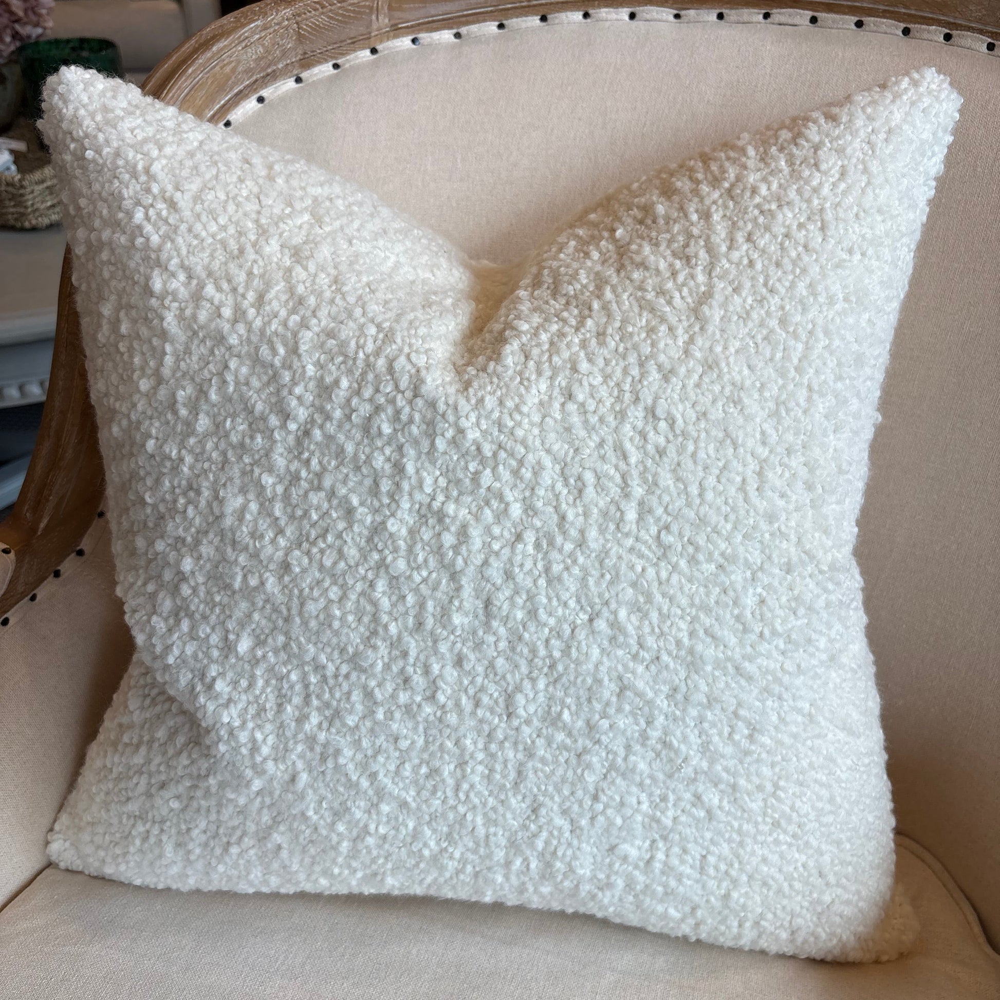 White textured pillow on a beige chair with a blurred background