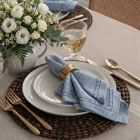 Elegant table setting with white plates, gold cutlery, and blue napkins.