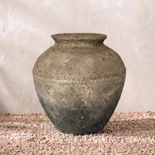 Vintage stone vase on a textured surface with a neutral background