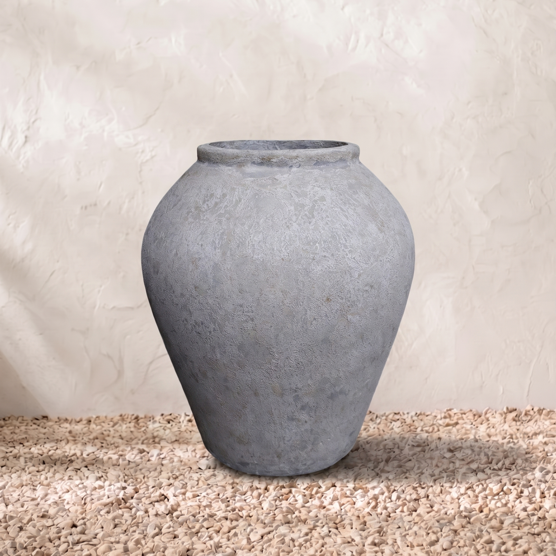 Gray terracotta pot on a textured surface with a neutral background