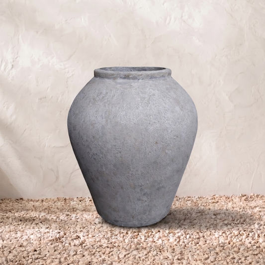 Gray terracotta pot on a textured surface with a neutral background
