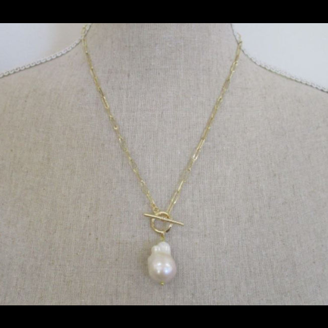 Gold necklace with a pearl pendant on a mannequin bust.