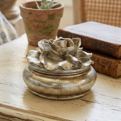 Decorative metal flower on a wooden table with books and a plant in the background