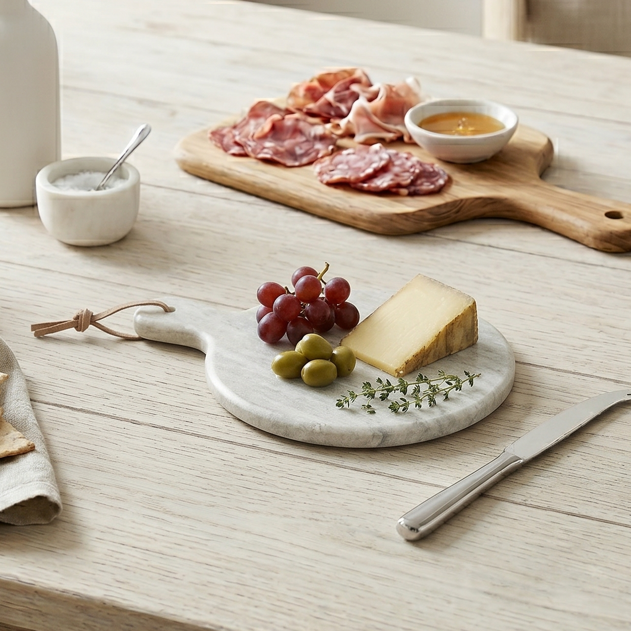 Dining table set with charcuterie board, wine glasses, and utensils in a bright room.