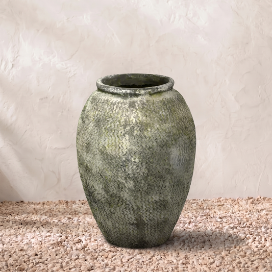 Green textured vase on a beige surface with a light gray background