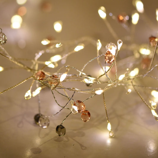 Light up any space with these stylishly designed Coco Cluster Fairy String Lights, boasting 100 warm LED lights and adorned with delicate crystals to create a dazzling atmosphere on your Christmas table, jar, or mantelpiece.