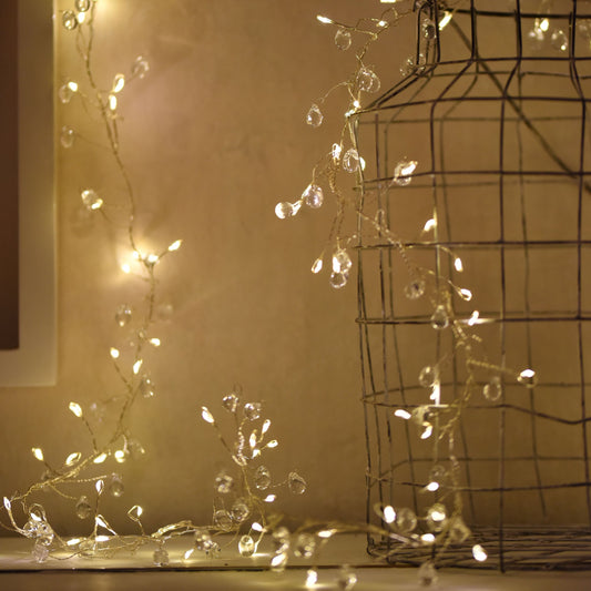 This set of decorative Crystal Cluster Fairy String Lights will add a touch of sophistication to any table or mantel with its 100 warm LED lights and shimmering clear crystals. Detail.