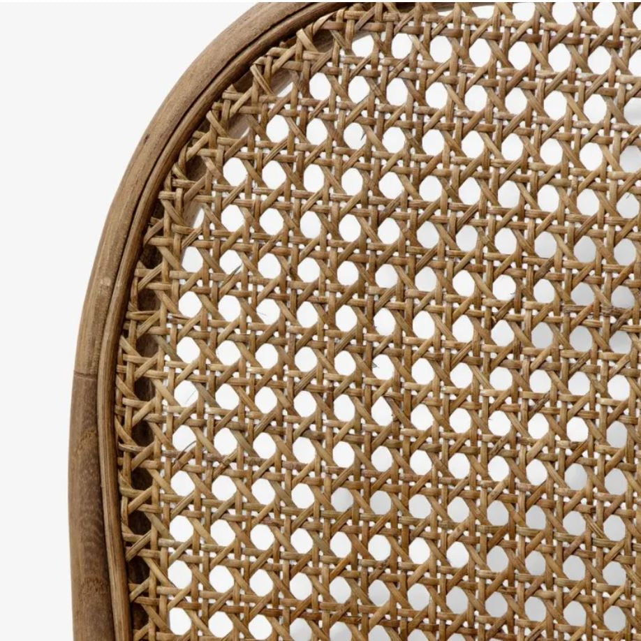 Close-up detail of a woven cane or rattan chair back with a curved natural wood frame, showing the texture and pattern of the woven material against a white background.