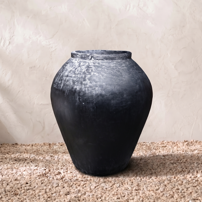 Black vase on a textured surface with a neutral background