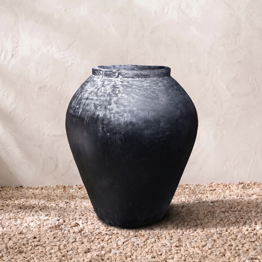 Black vase on a textured surface with a neutral background