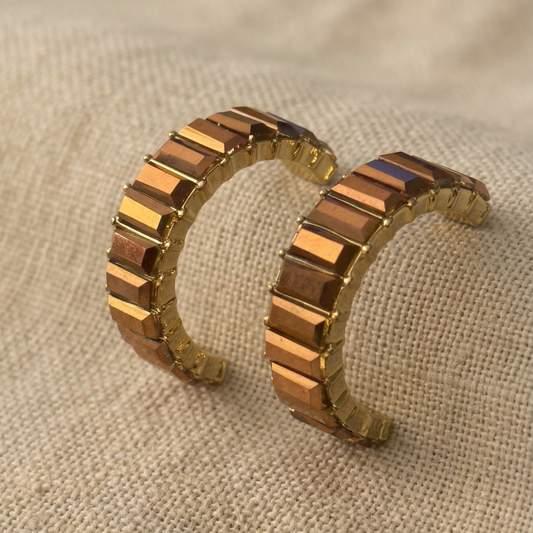 Pair of crystal hoop earrings on a textured beige surface