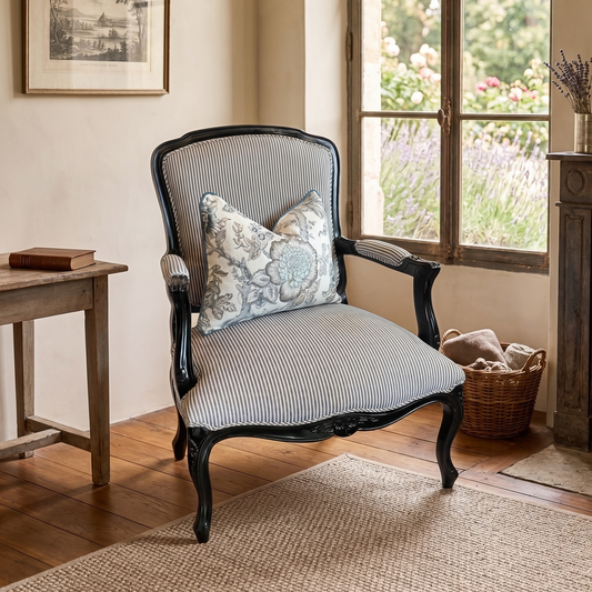 Decorative armchair with cushions in a room with a window, table, and fireplace.