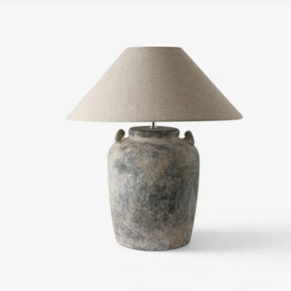 Table lamp with a textured base and beige lampshade on a white background