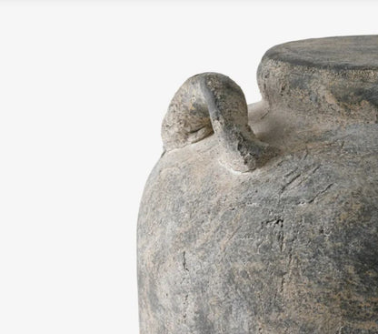 Close-up of a stone vase with a decorative handle on a white background
