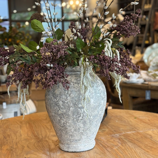Decorative vase with flowers on a wooden table in a blurred indoor setting