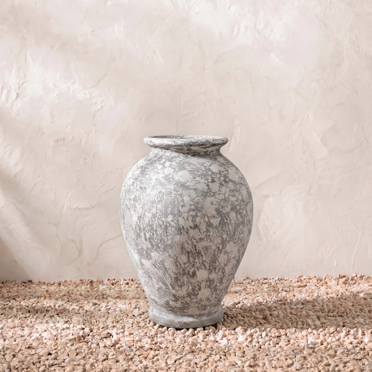 Decorative stone urn on a textured surface with a neutral background