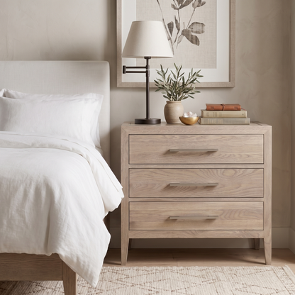 Neatly made bed with a wooden nightstand featuring a lamp and decor items.