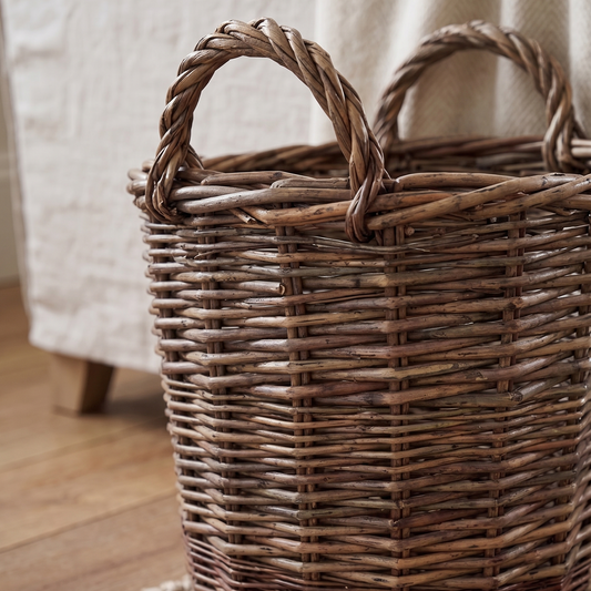 Woven basket on a wooden floor with a textured rug and light-colored fabric in the background