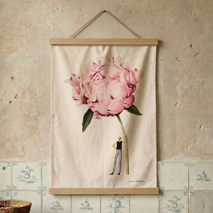Floral tea towel with a person inside a pink flower hanging on a textured wall.