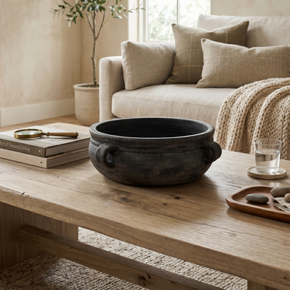 Living room with a wooden coffee table, black pot, books, and a plant.
