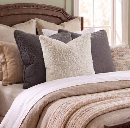 Bed with decorative pillows and a wooden headboard in a bedroom setting.