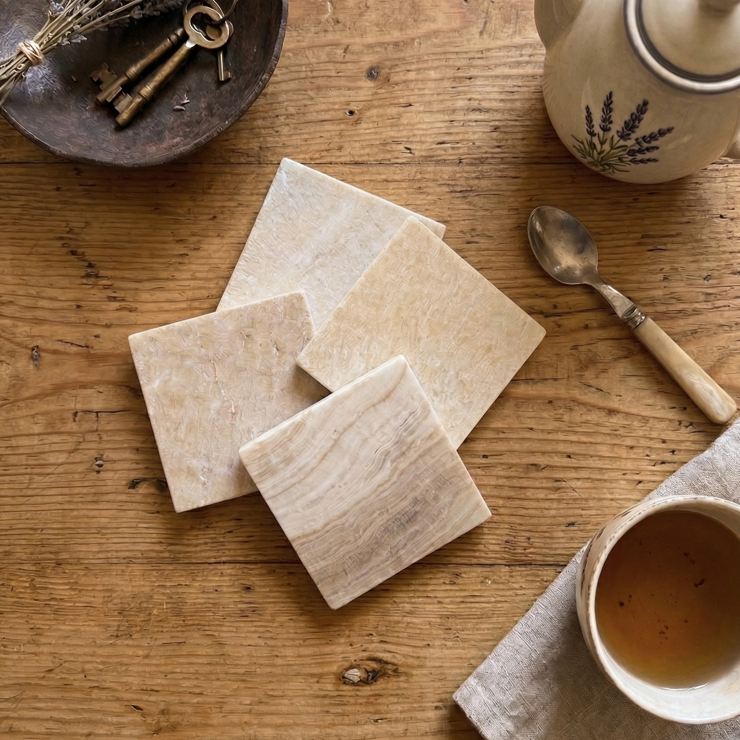 Wooden table with stone coasters, teapot, cup, and spoon on a rustic setting