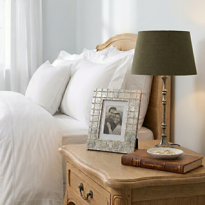 Bedroom with wooden nightstand, lamp, and photo frame.