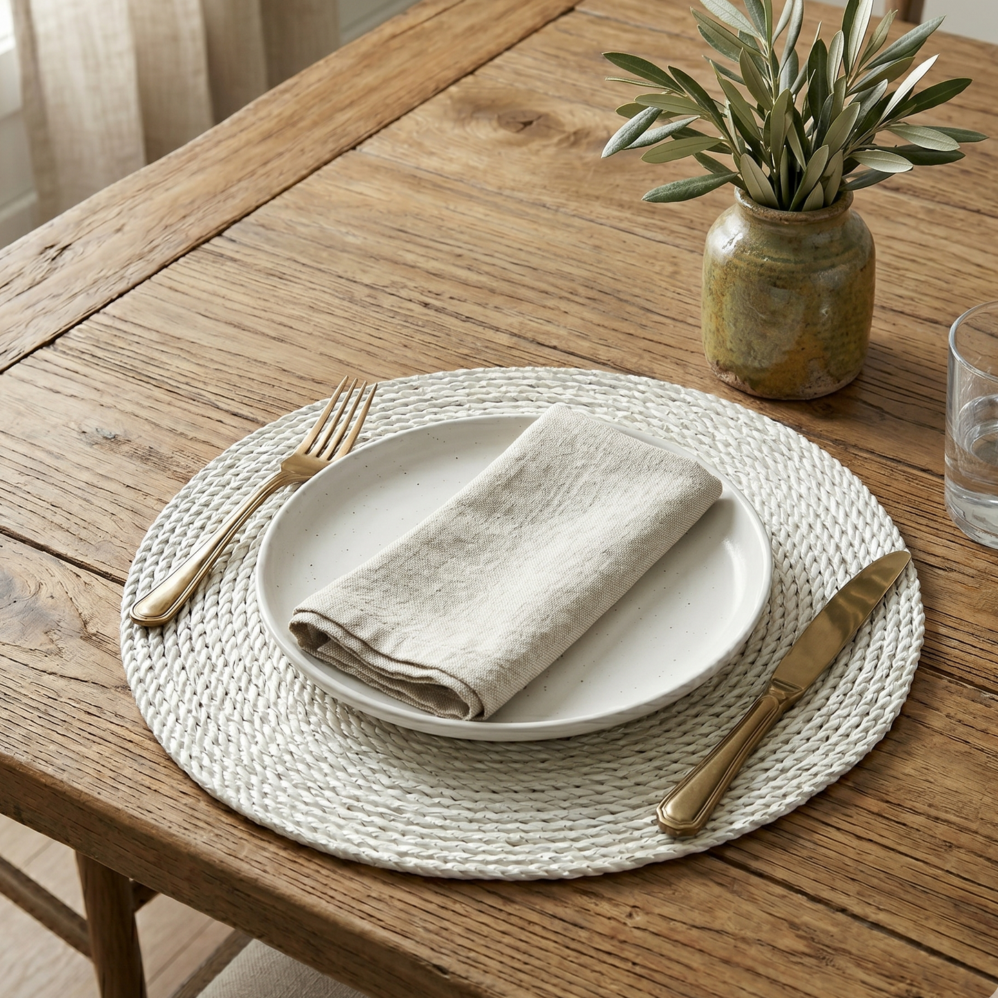 Dining table setting with plates, napkin, fork, and knife on a woven placemat.
