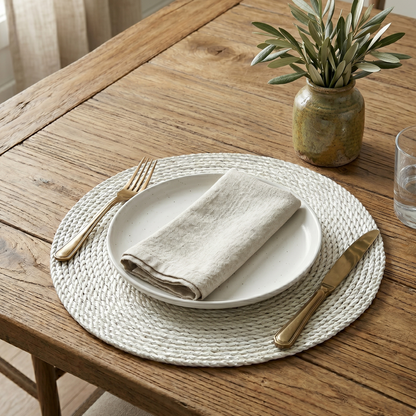 Dining table setting with plates, napkin, fork, and knife on a woven placemat.