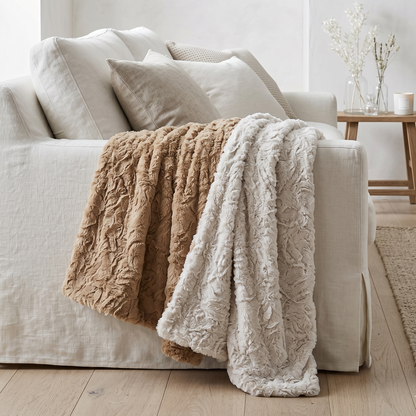  textured throw blankets in beige and cream draped over a sofa in a living room setting.