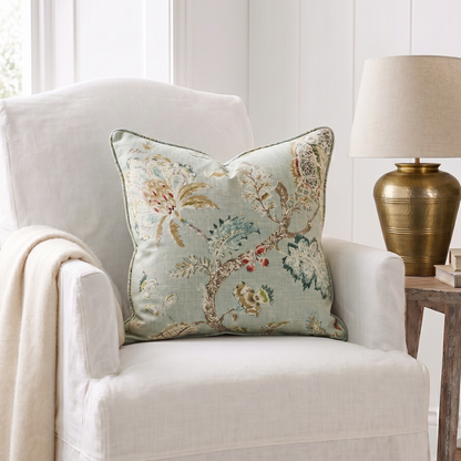Decorative pillow on a white armchair with a lamp in the background