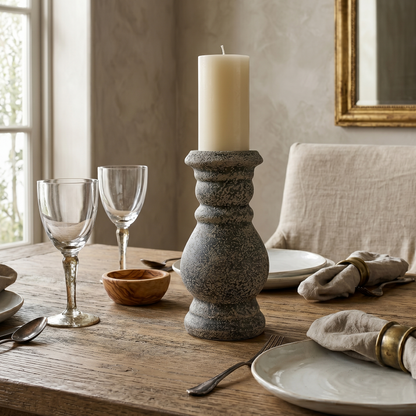 Dining table setting with candle holder, plates, and glasses in a cozy room.