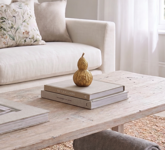 Beige sofa with decorative pillows and a wooden coffee table with books and a gourd.