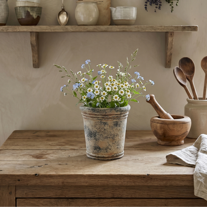 Nostalgic kitchen scene with wooden table, potted flowers, and shelves with kitchenware.
